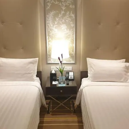 Dorsett Putrajaya Hotel Bagian luar foto The photo shows a cozy hotel room featuring two twin beds with white bedding. Each bed has a neatly arranged white pillow. Between the beds is a small bedside table, which holds a lamp, a couple of decorative plants, and some electronic devices. The 