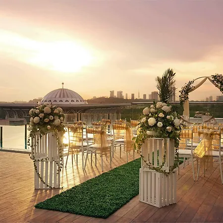 Dorsett Putrajaya Hotel Bagian luar foto The photo shows a beautifully designed outdoor wedding venue. In the foreground, there are elegant arrangements of flowers on white pedestals, creating a romantic atmosphere. There is a pathway lined with green grass leading to an arch adorned with f